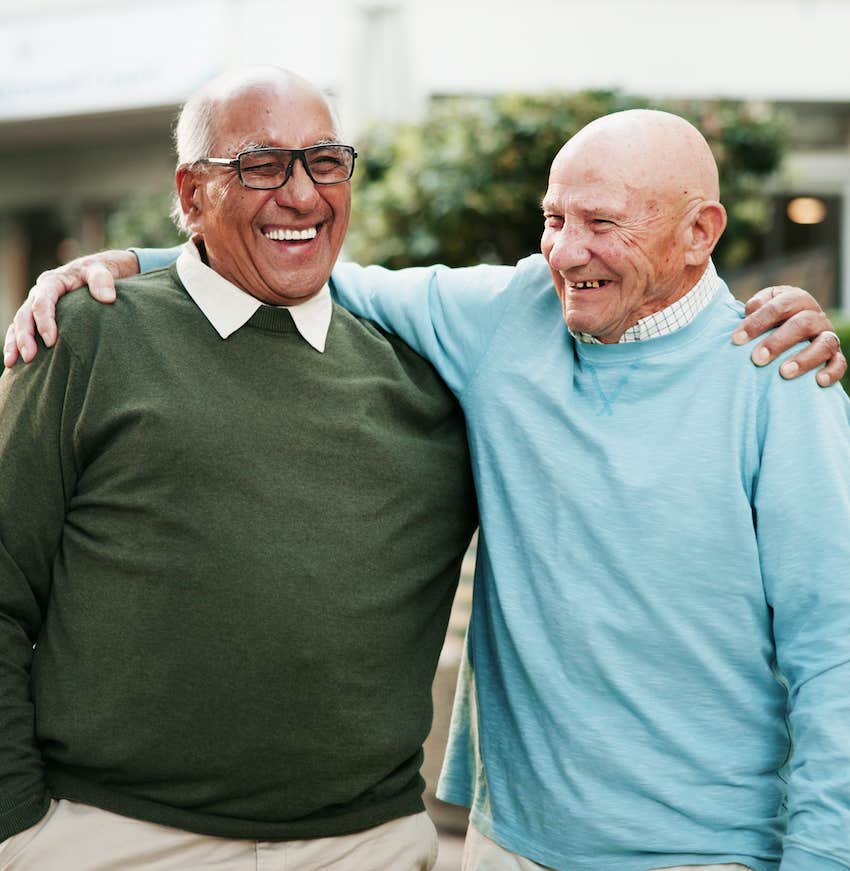 Two Very happy men laugh with arms around each other's shoulders