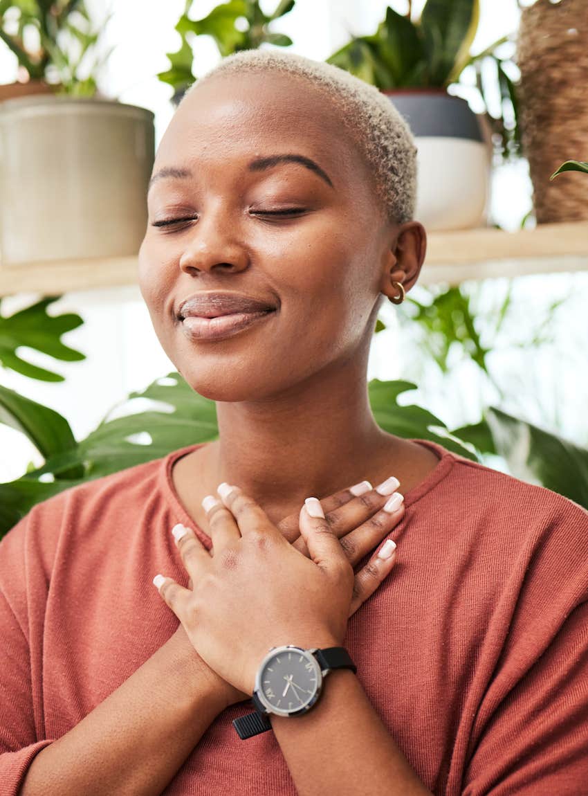 She places hands over her heart and closes eyes, her face is calm