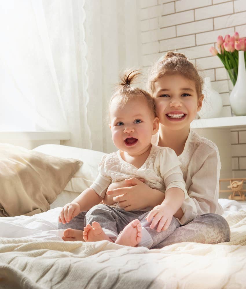 sisters hugging while sitting on a bed