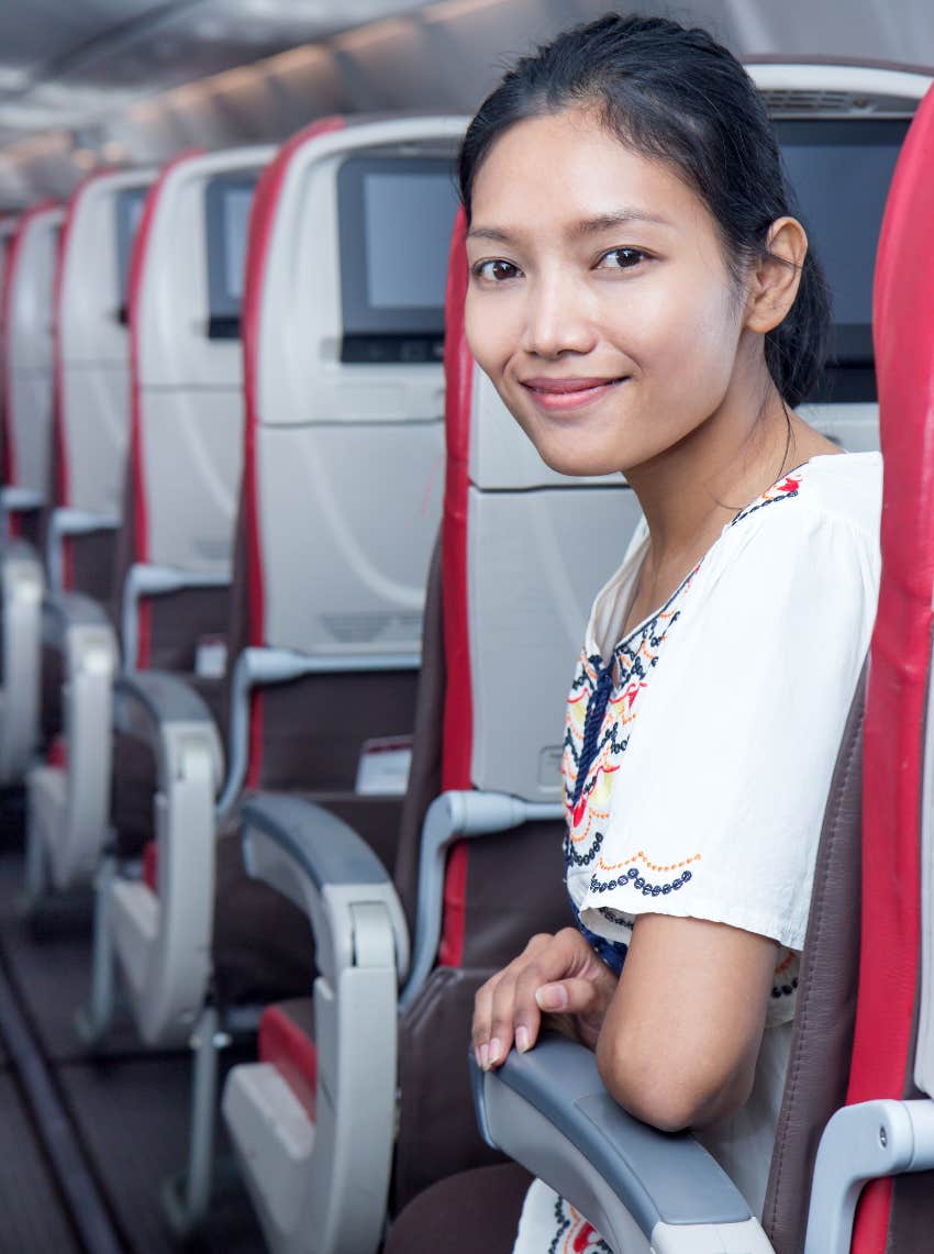 Happy woman in aisle seat of airplane