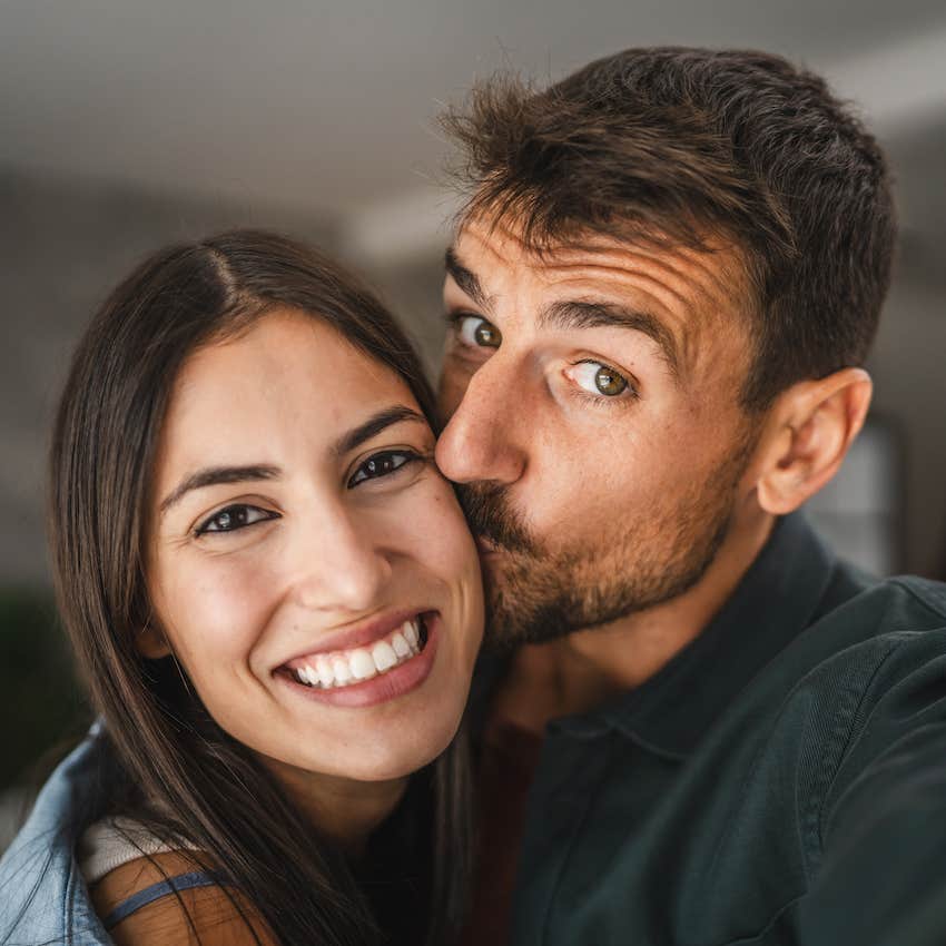 She smiles as he kisses her cheek