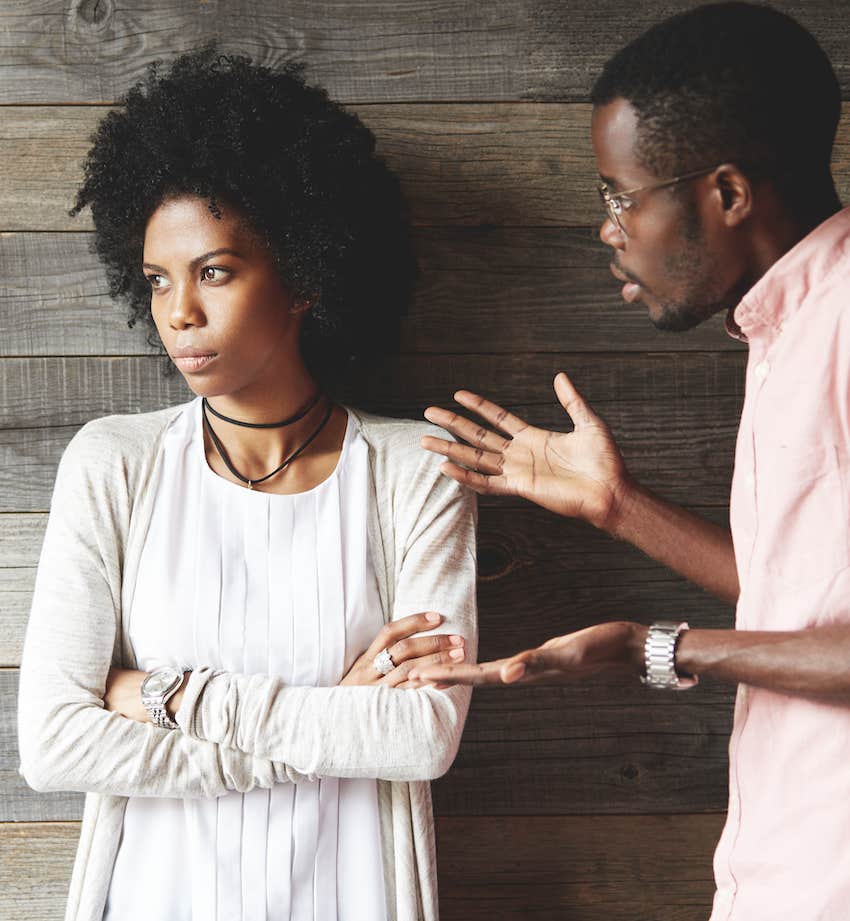 She turns away with arms crossed as he gestures frustration