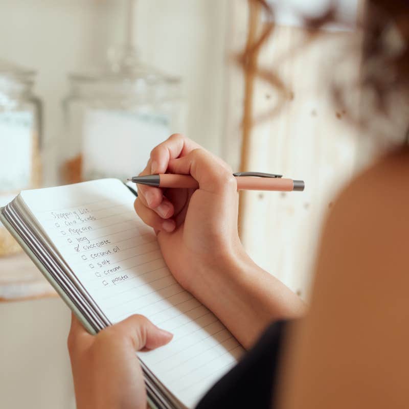 close up shot of woman writing list in notebook