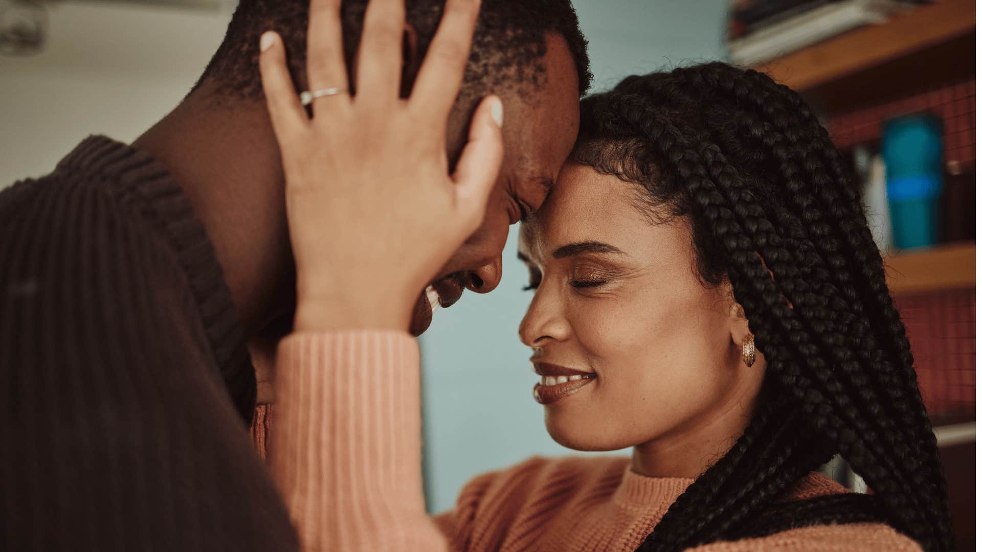 Forehead to forehead, she places hands on either side of his head, they both smile.