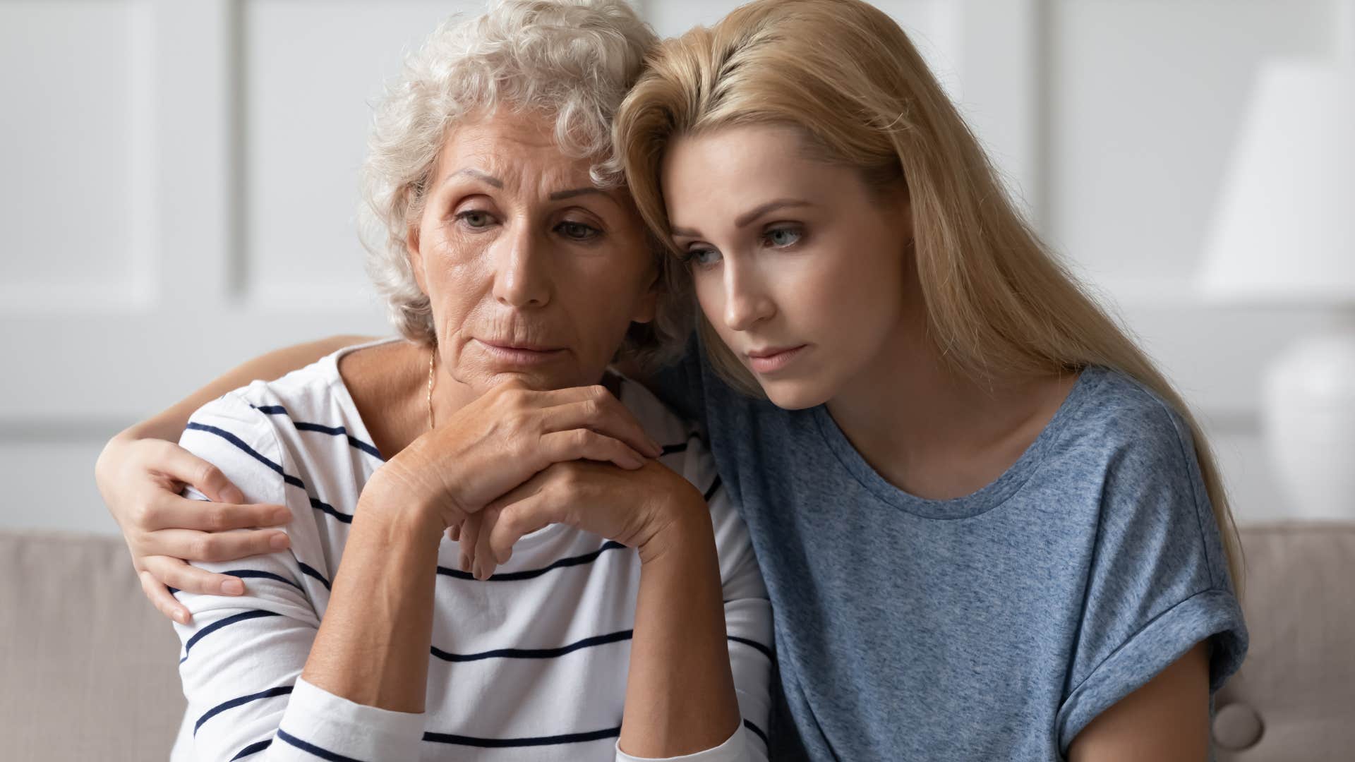 Adult daughter looking upset and hugging her mother.