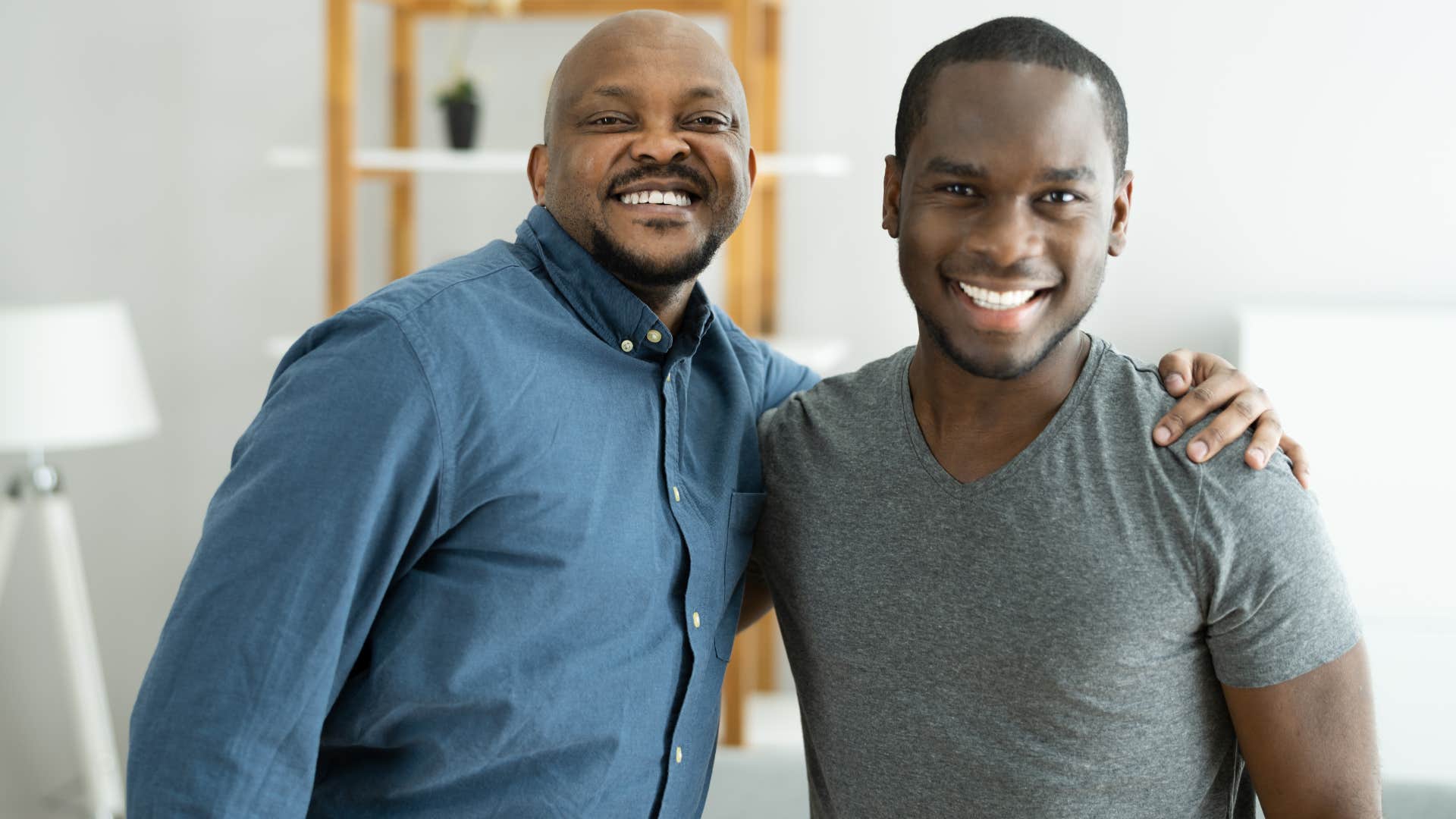 Dad and adult son smiling at the camera.