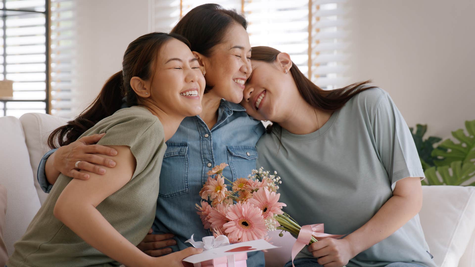 Mother hugging her two adult daughters.