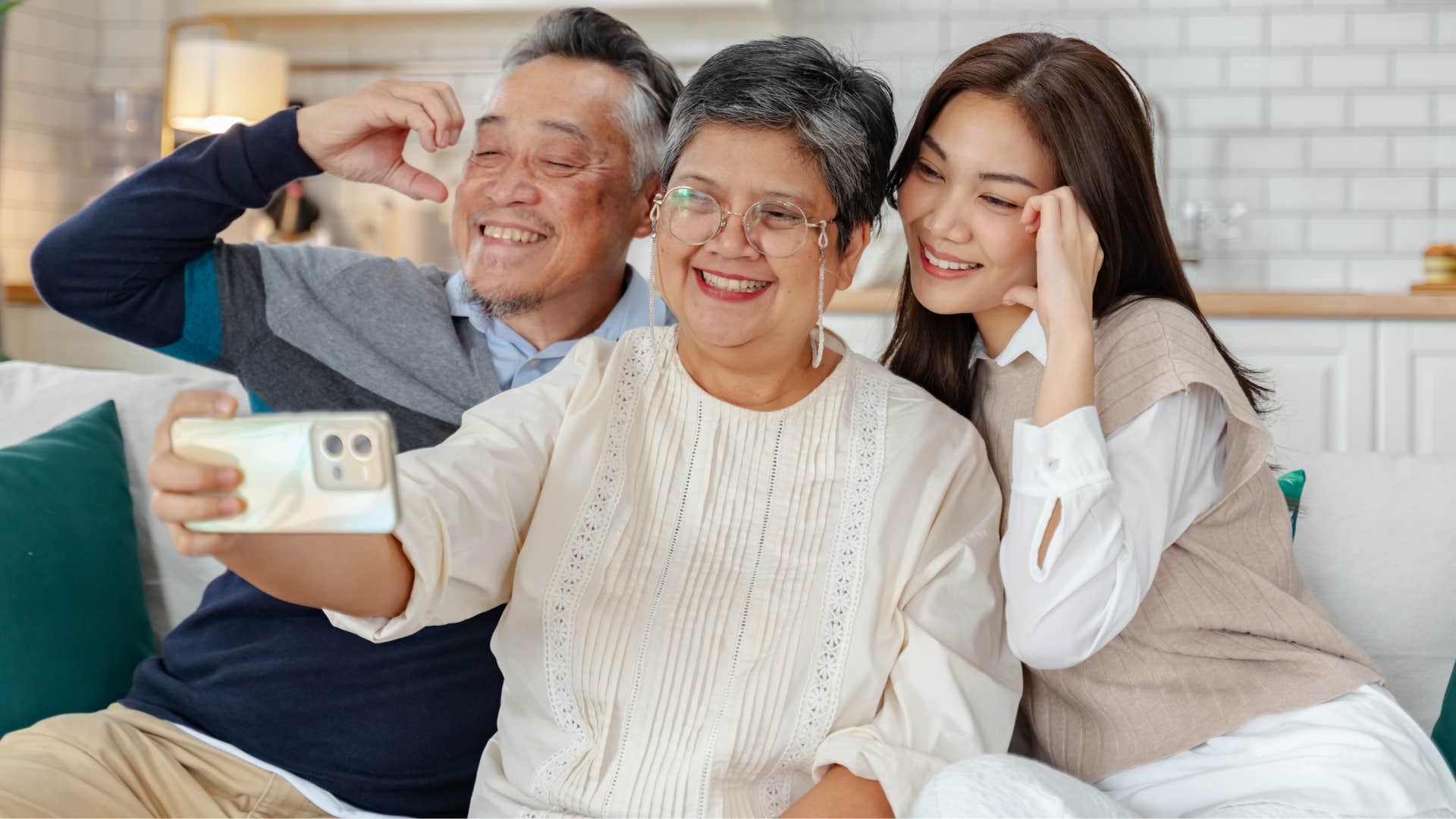 Father and mother taking a picture with their adult daughter.