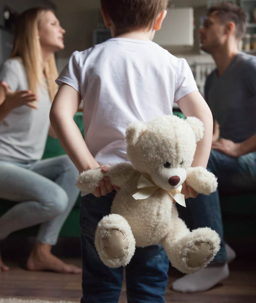 Child holds stuffed bear behind back as parents argue