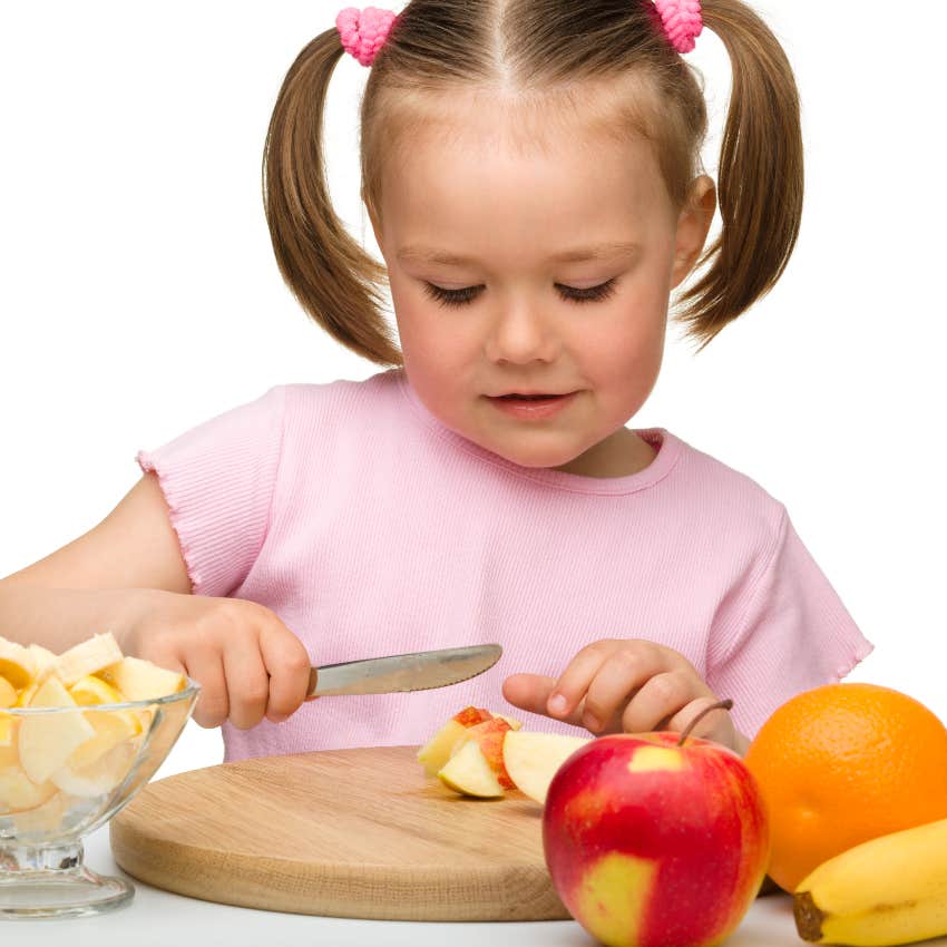 Independent kid cutting an apple