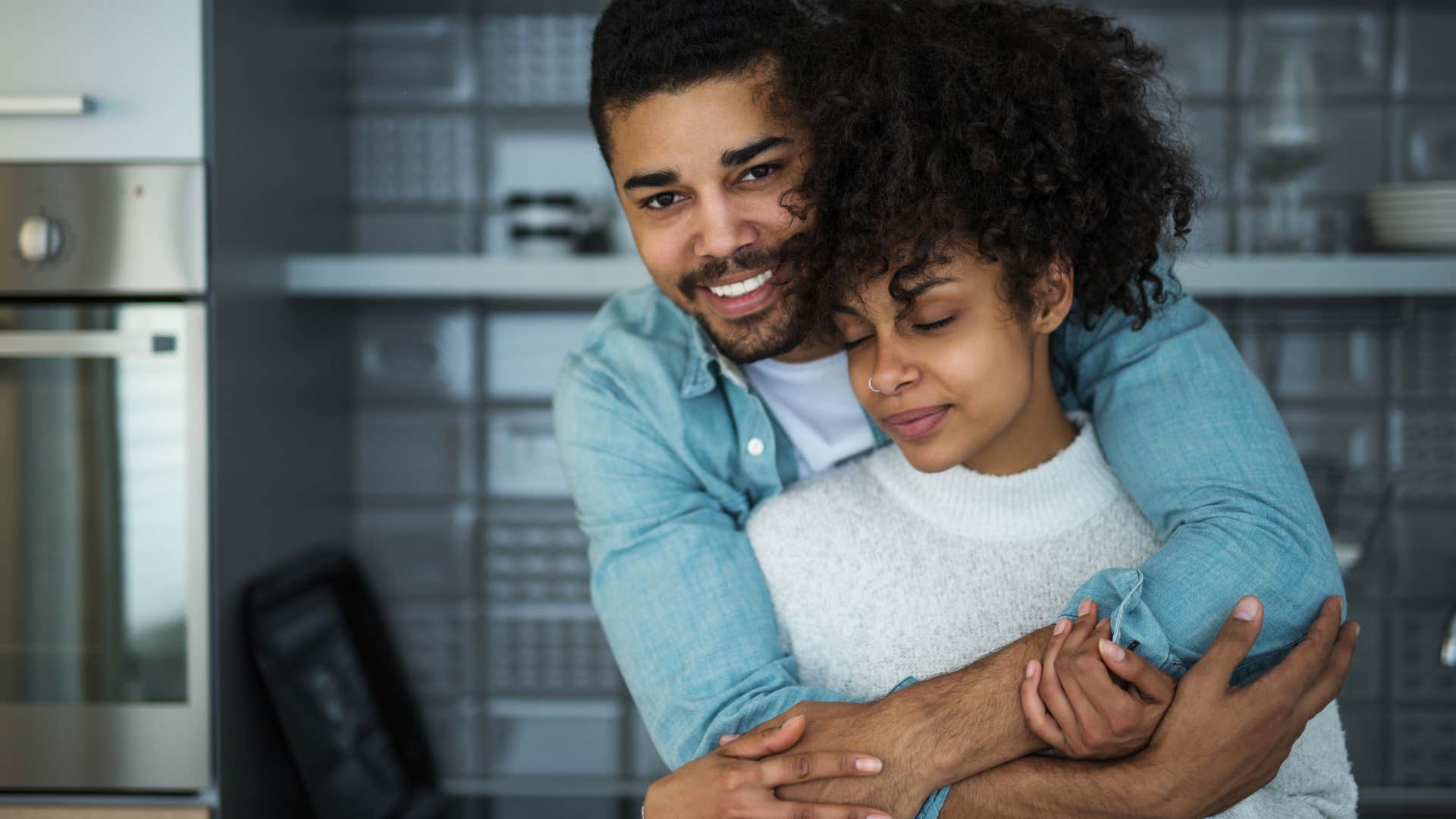 Man hugging his wife in their kitchen.