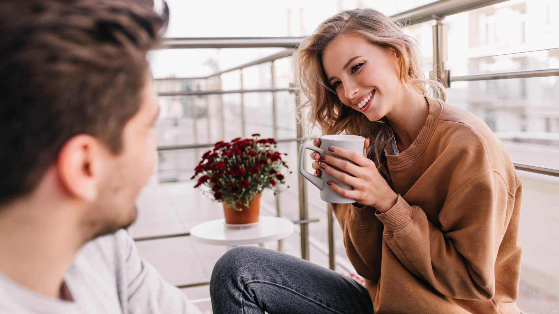 Woman smiling at a man with a cup of coffee in her hands.