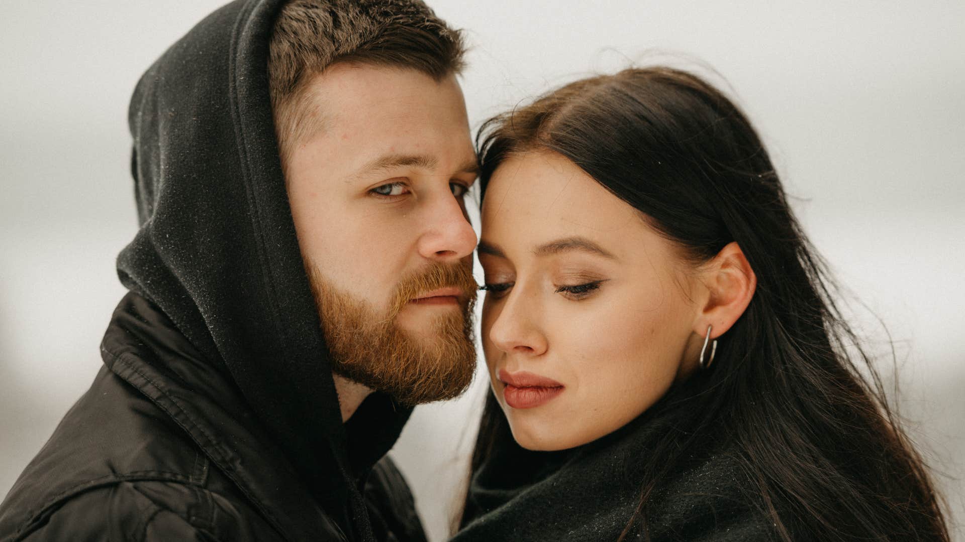 Woman and man hugging outside looking solemn. 