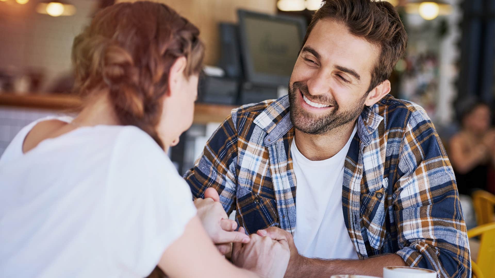 Man smiling at a woman across the table from him.