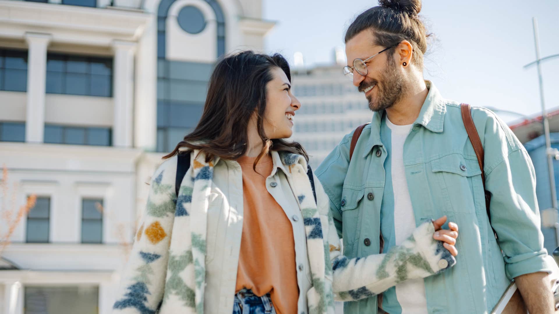 Man and woman smiling at each other while walking outside. 