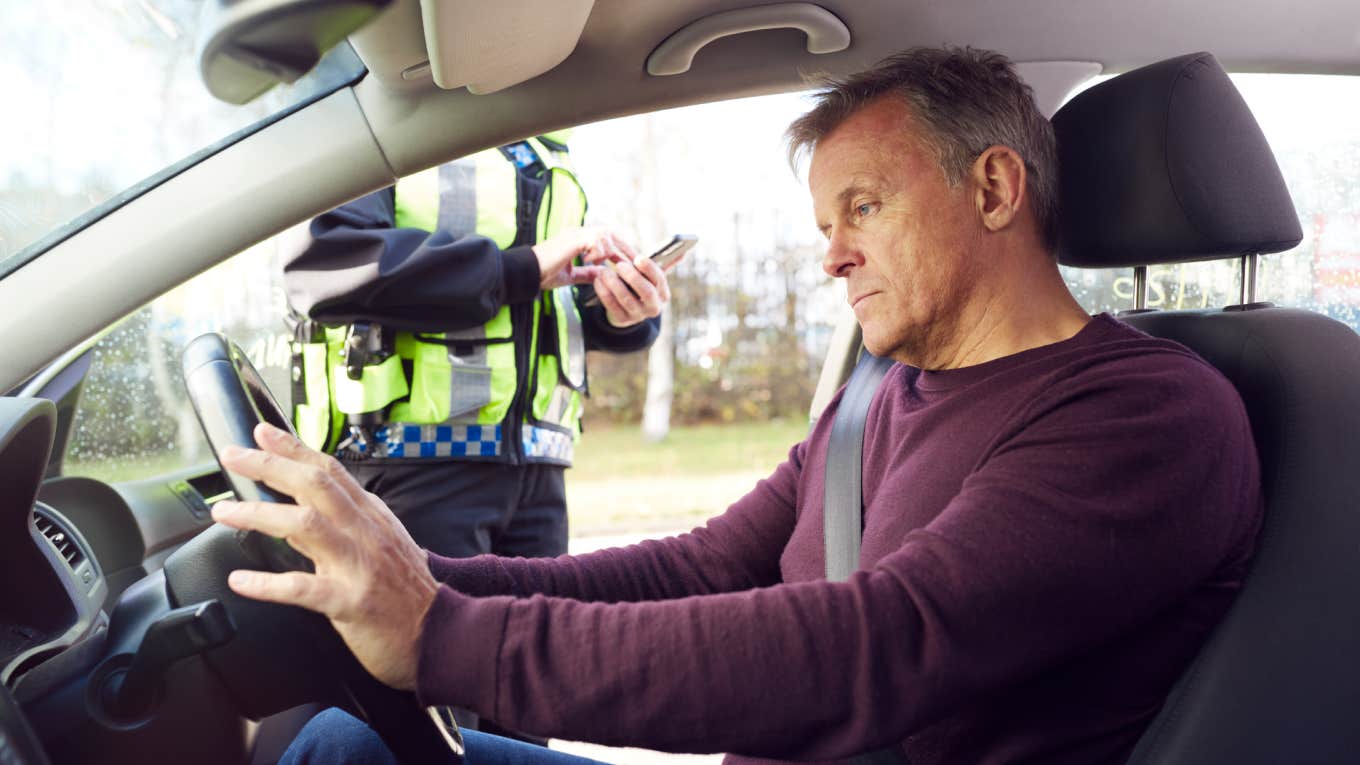 cop pulling over frustrated driver sitting in car with hands on wheel