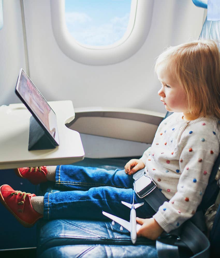 little girl using tablet on airplane