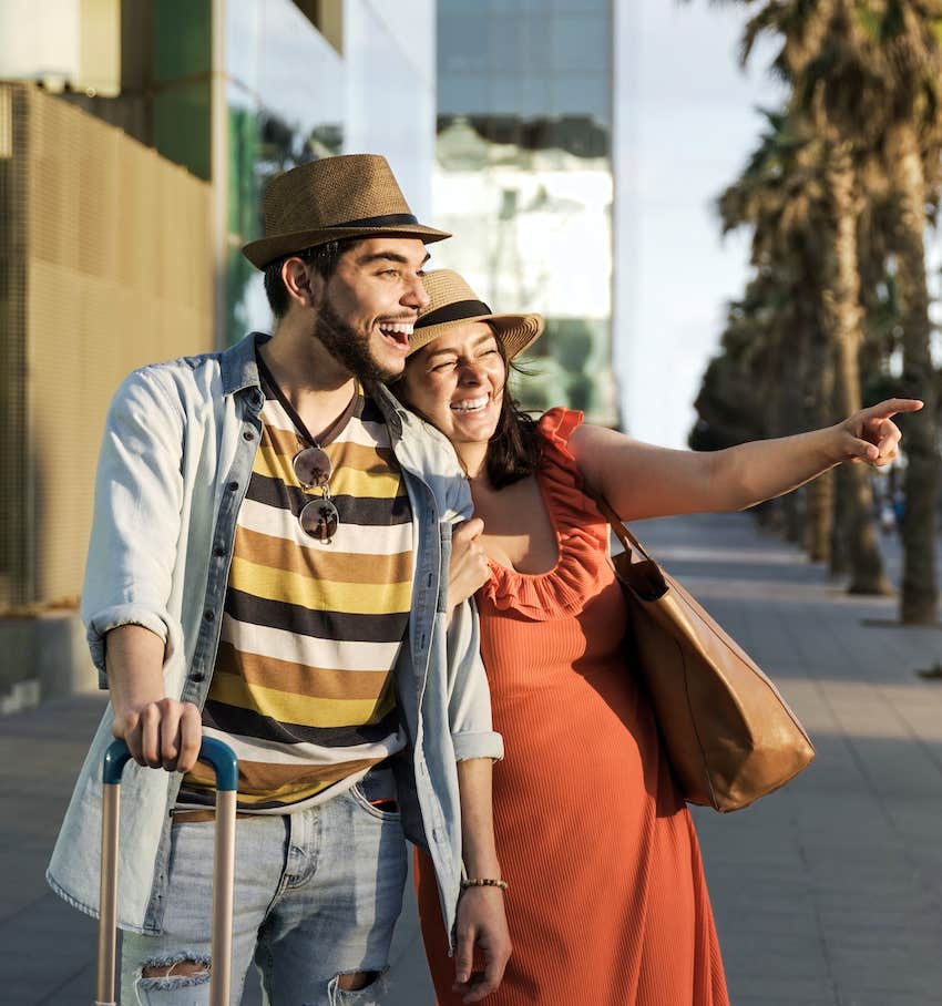 Couple walk in city, she points at something 