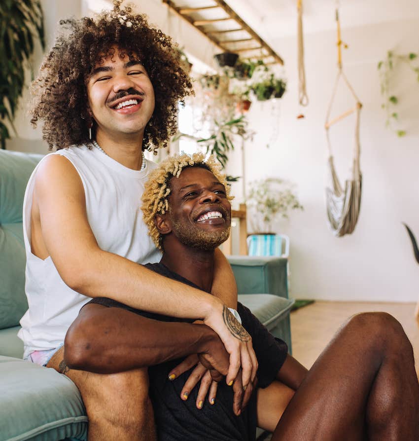 Smiling couple cuddles while sitting with arms entwined