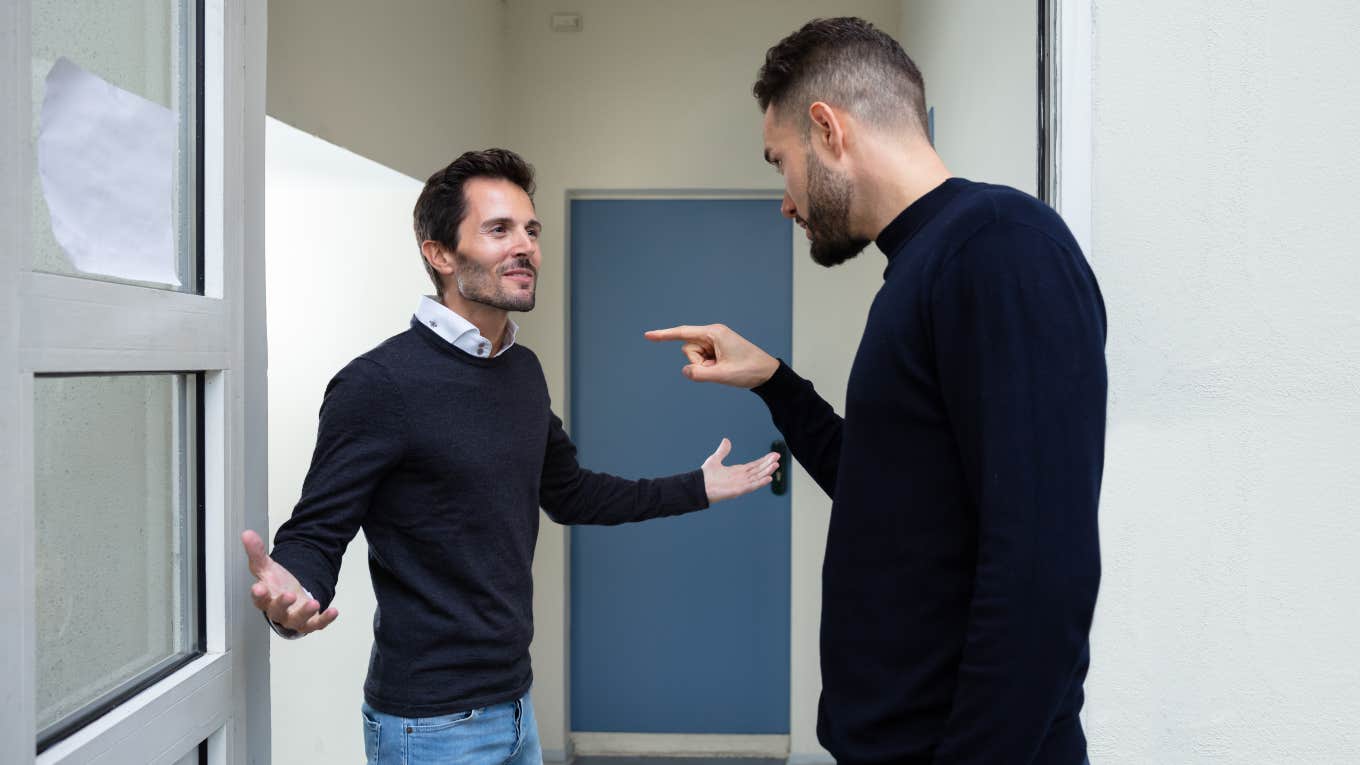 two men arguing in front of a door