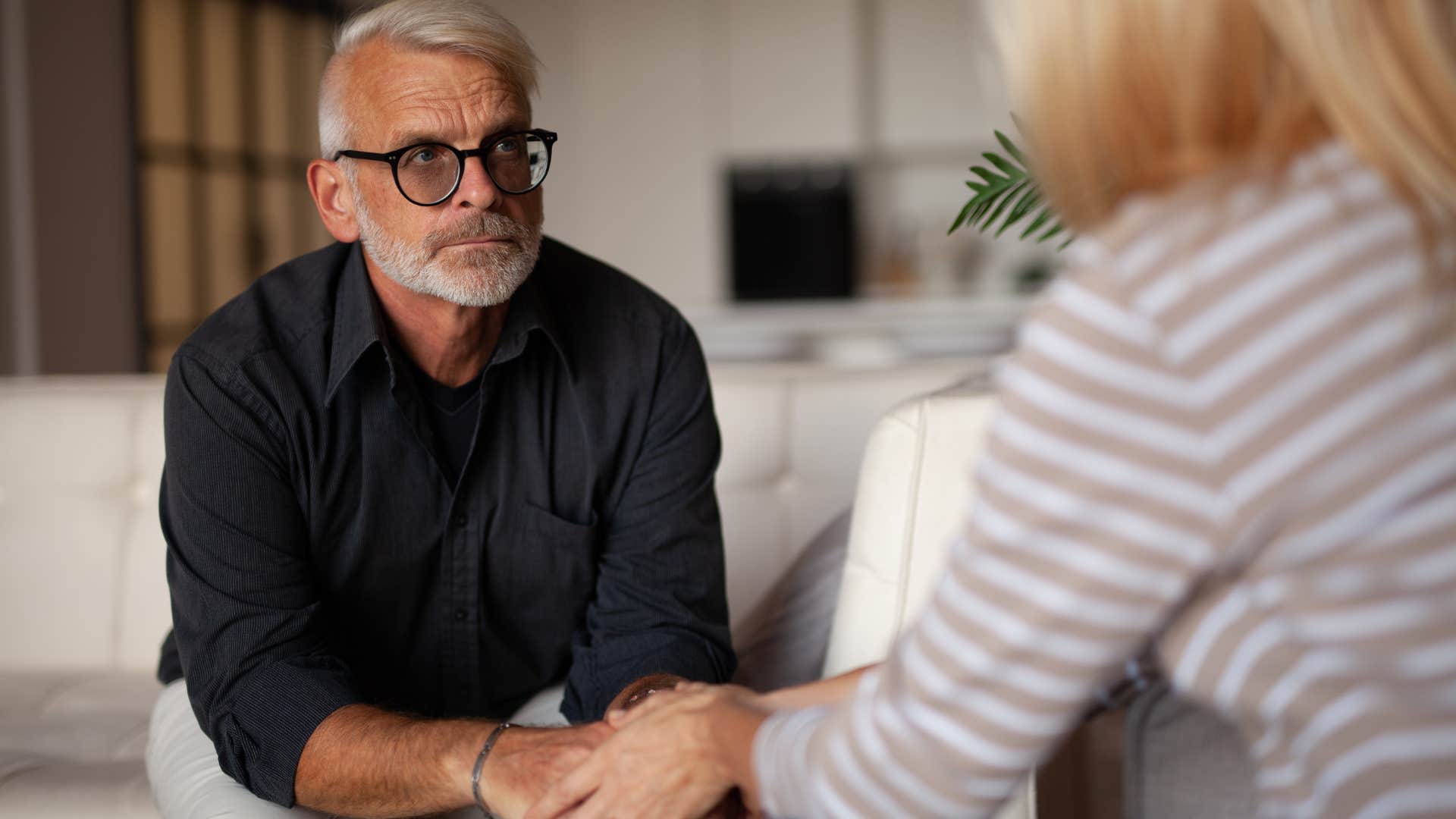 Empathetic man holding a woman's hand and listening. 