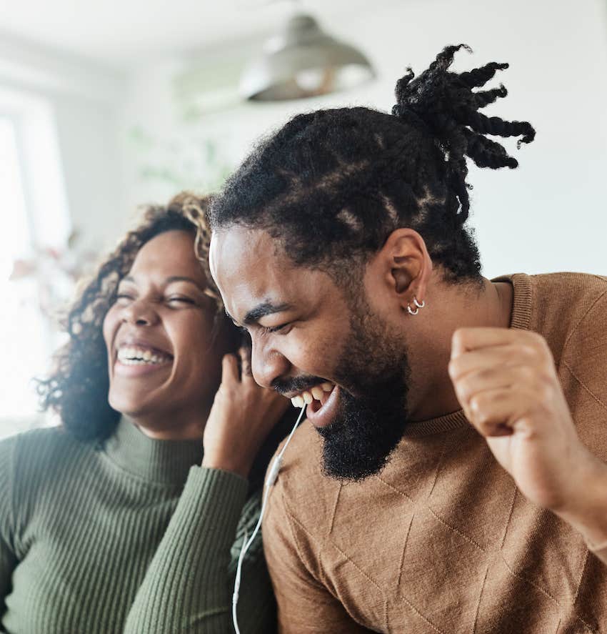 Couple laughs and raises hands