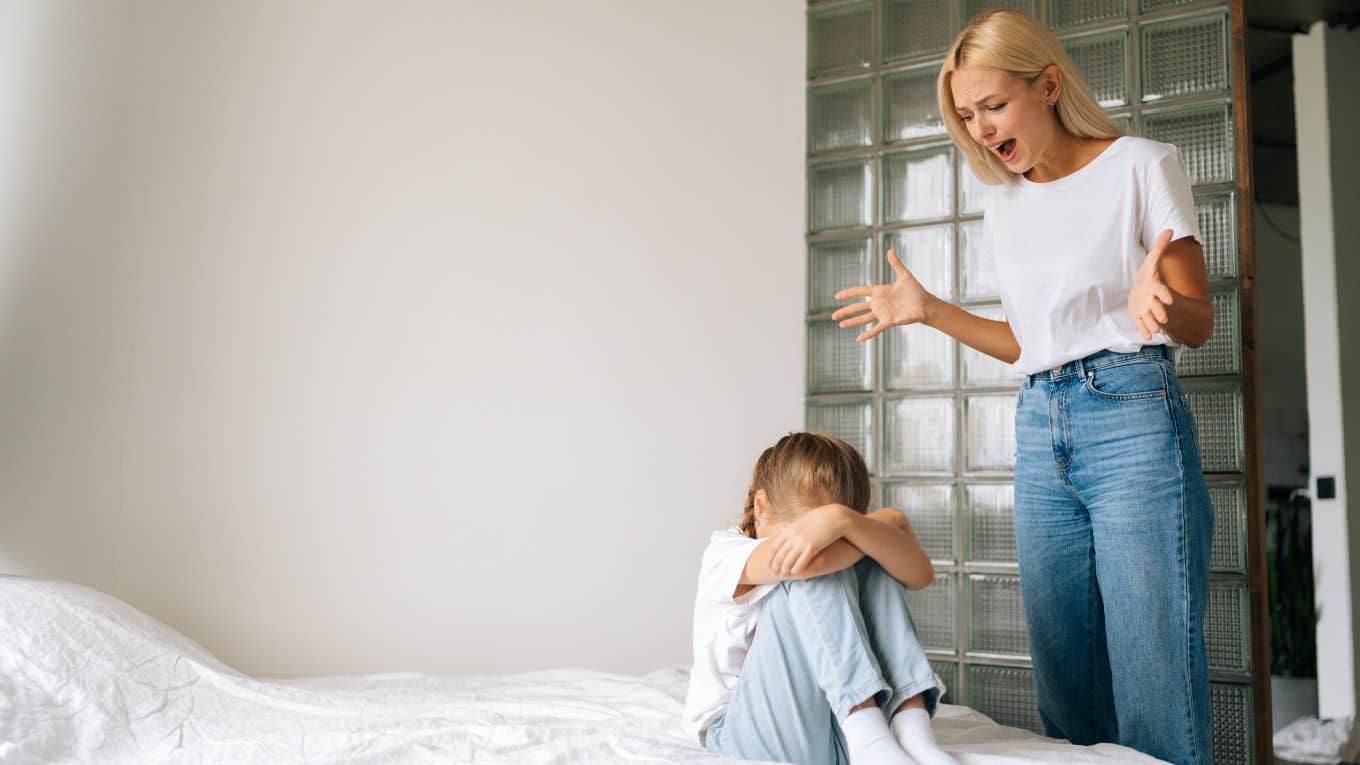 angry mother yelling at her little girl who is on the bed with her face covered