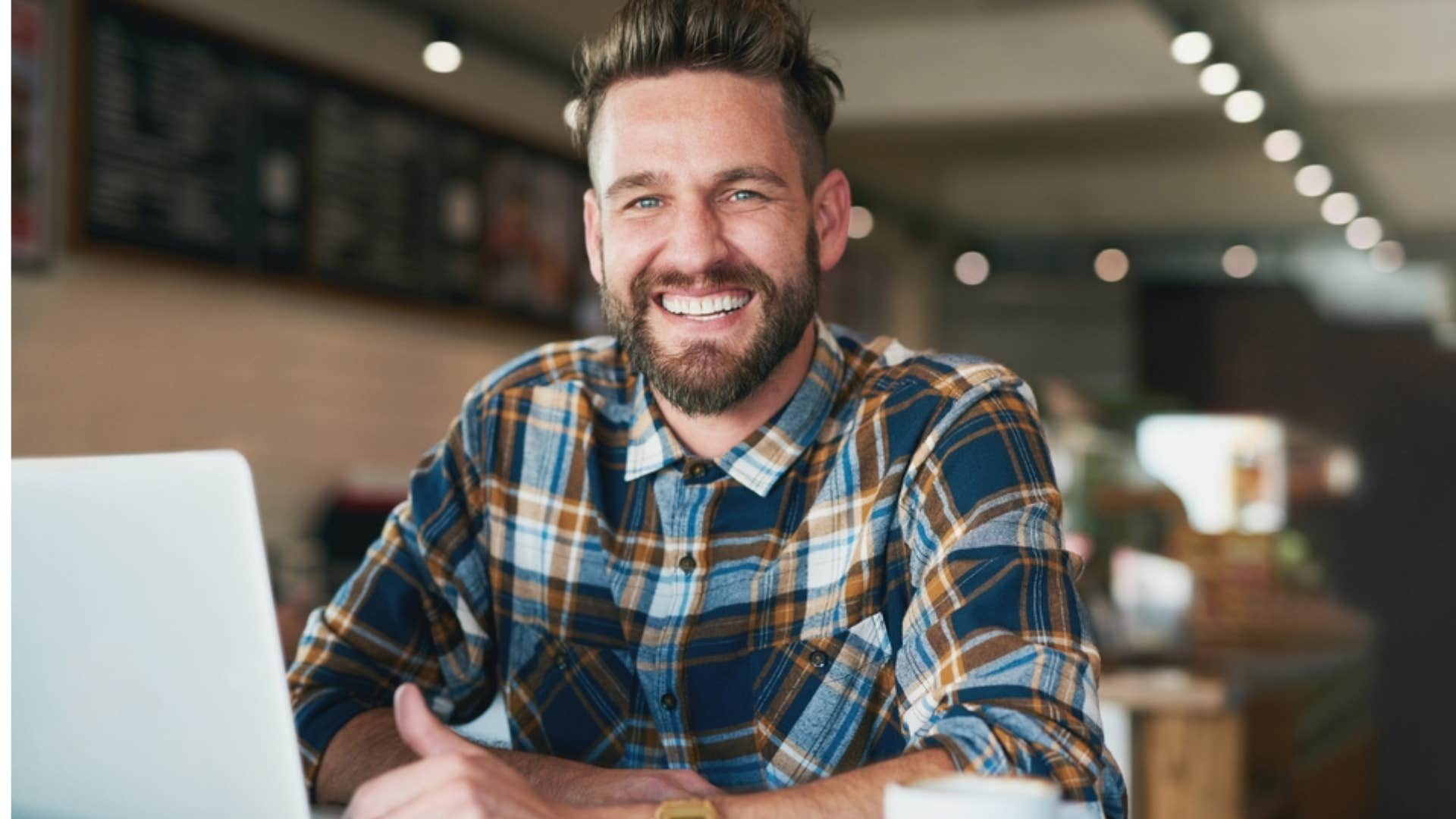 Man smiling sitting alone at a coffee shop. 