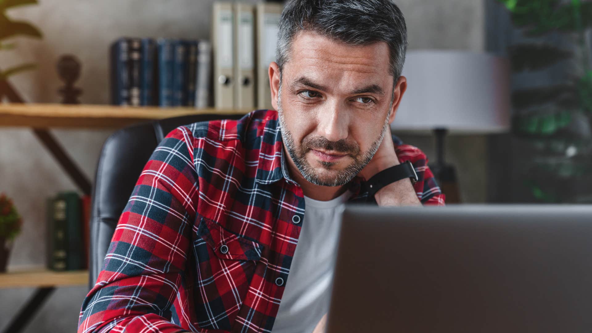 Man looking tired staring at his laptop. 