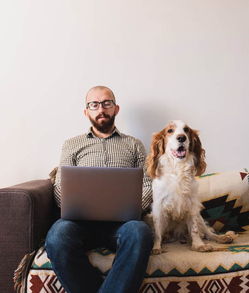 Man working from home sitting on a couch with his dog