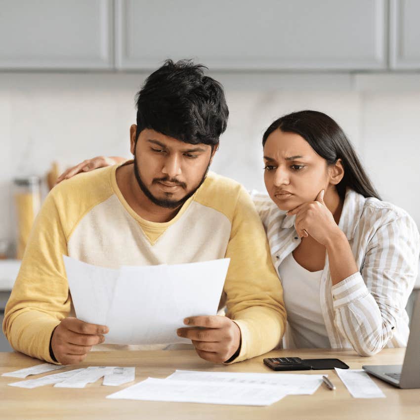 Couple looks at paperwork and frown