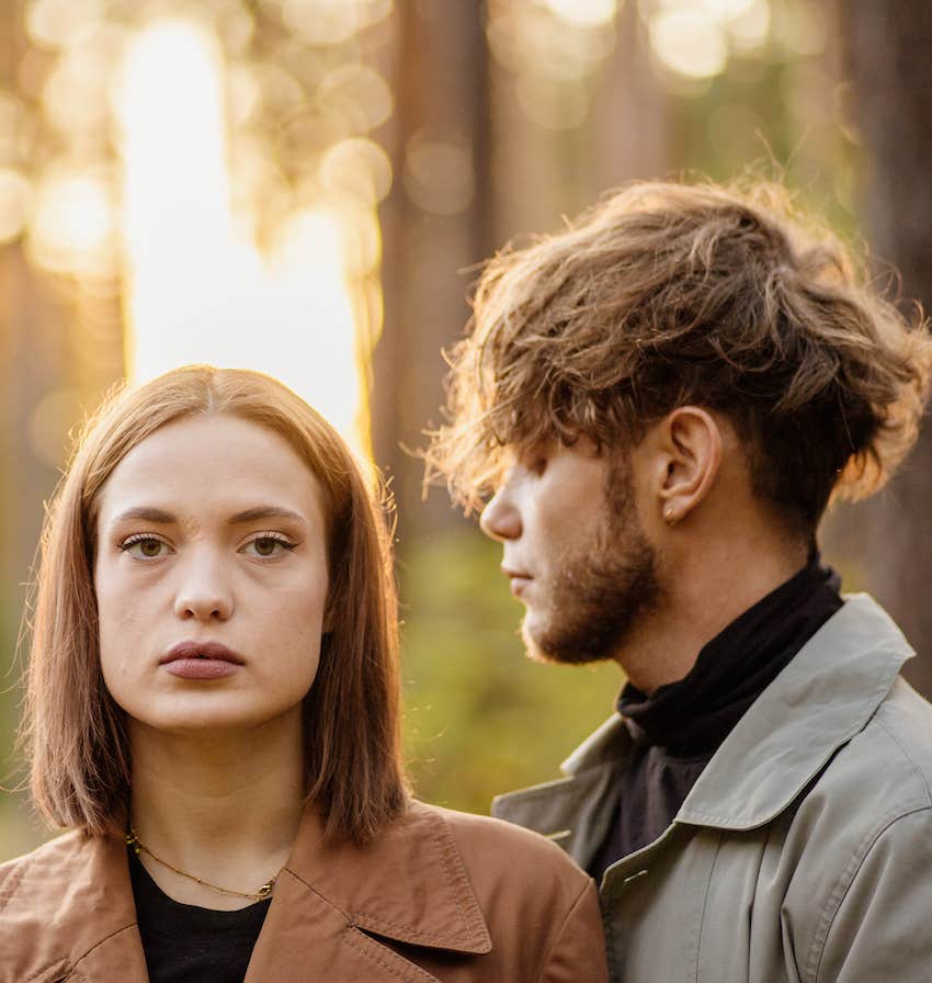 She looks blankly at camera as he looks intently at her