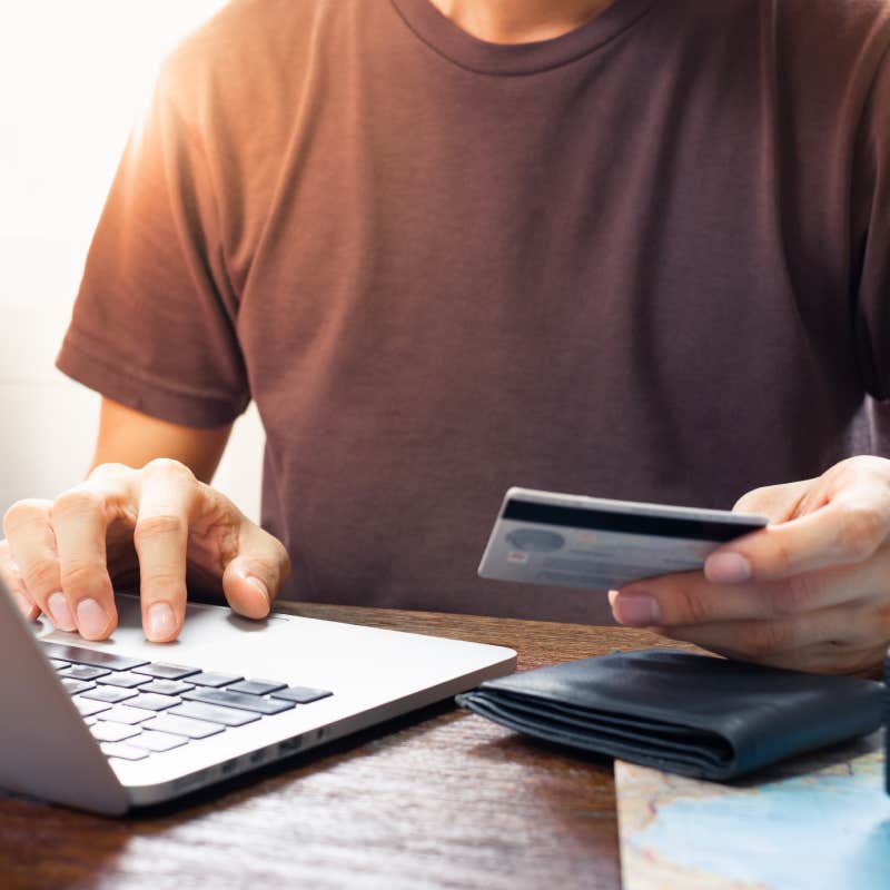 close up shot of man using card to buy something on laptop