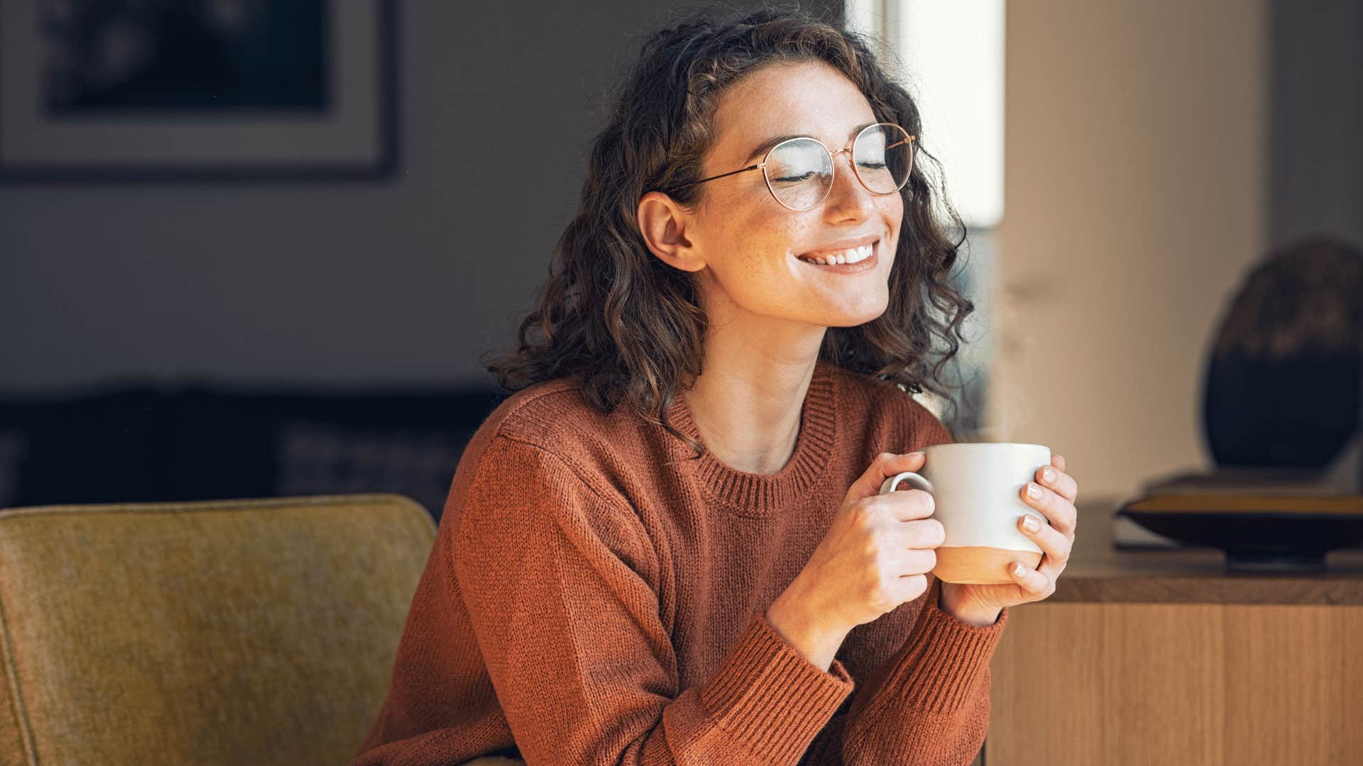 woman smiling while drinking coffee