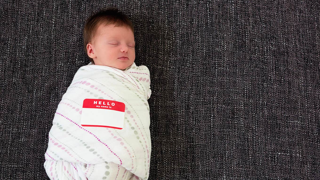 Swaddled infant wearing name sticker