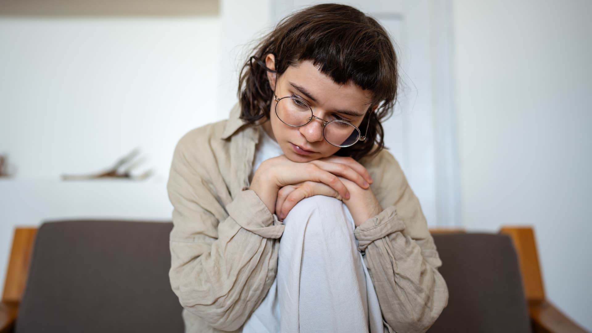 Woman looking nervous sitting on her couch.