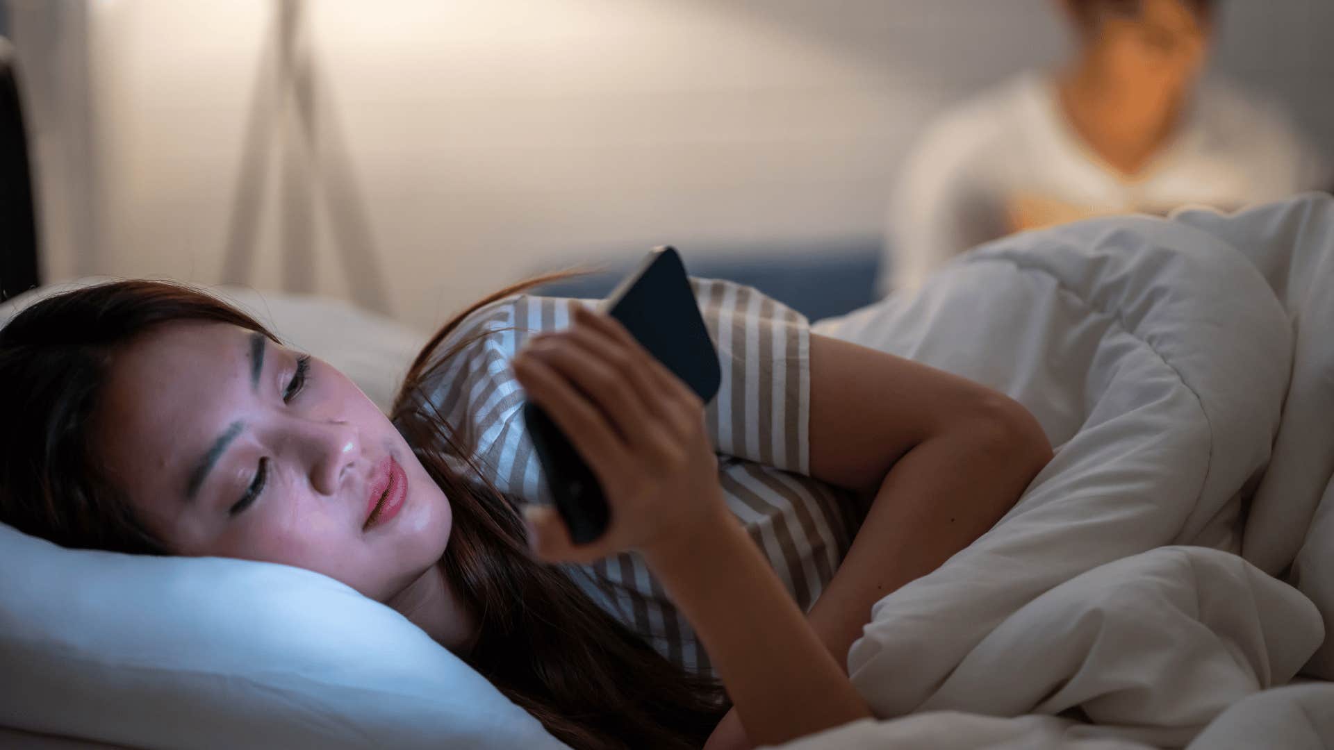 woman looking at phone while laying down 