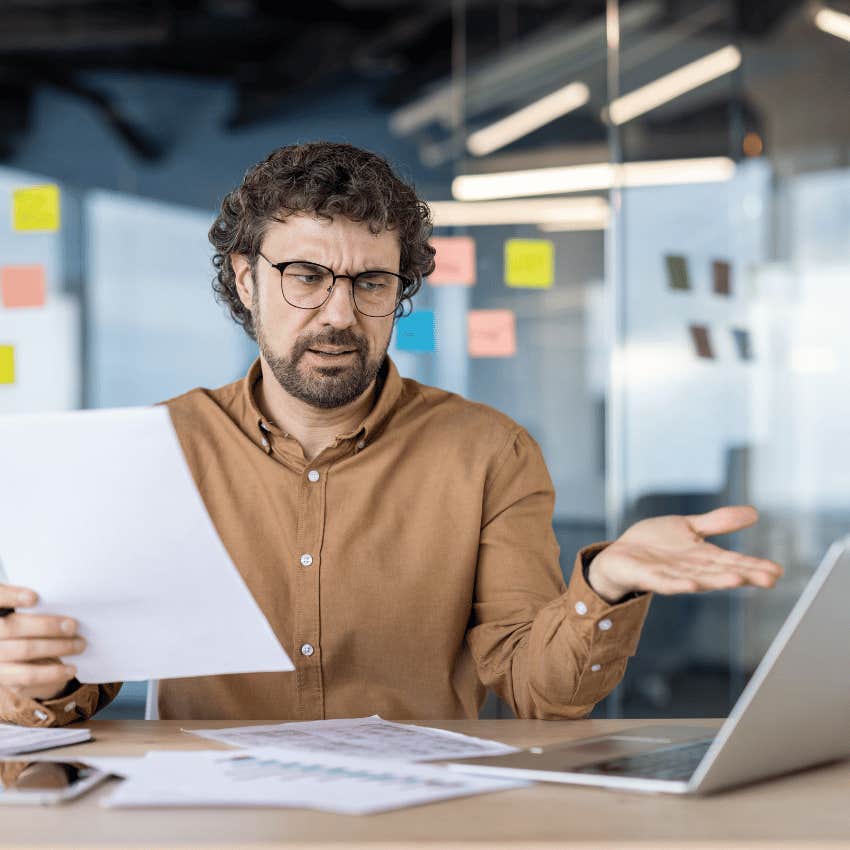 older man pointing at laptop in frustration