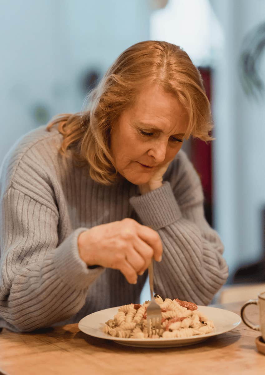 older woman eating pasta alone