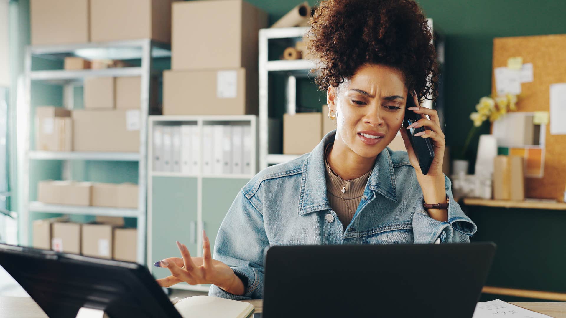 Woman looking annoyed on the phone at her work desk.