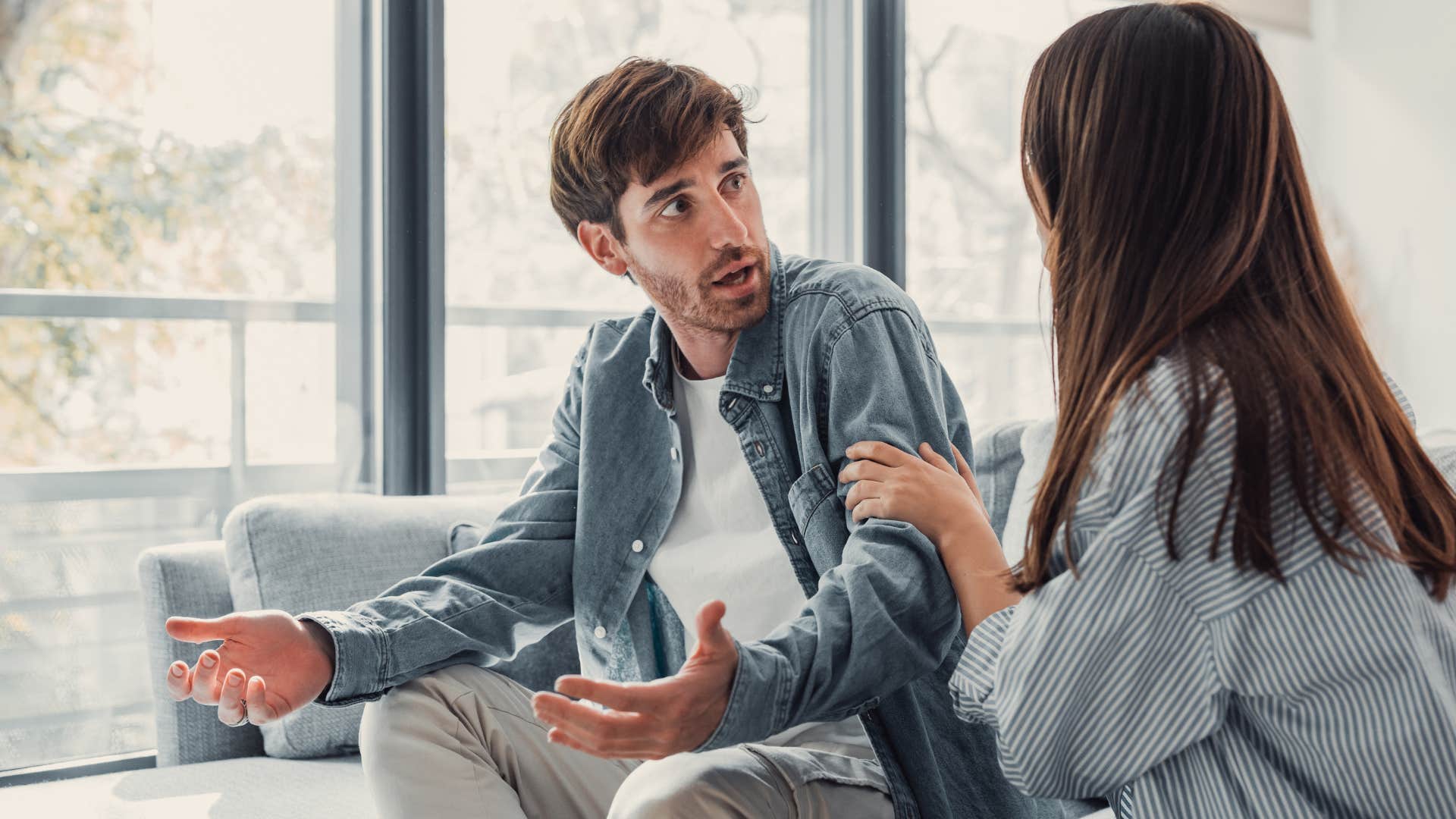 Man looking upset at his girlfriend on the couch.