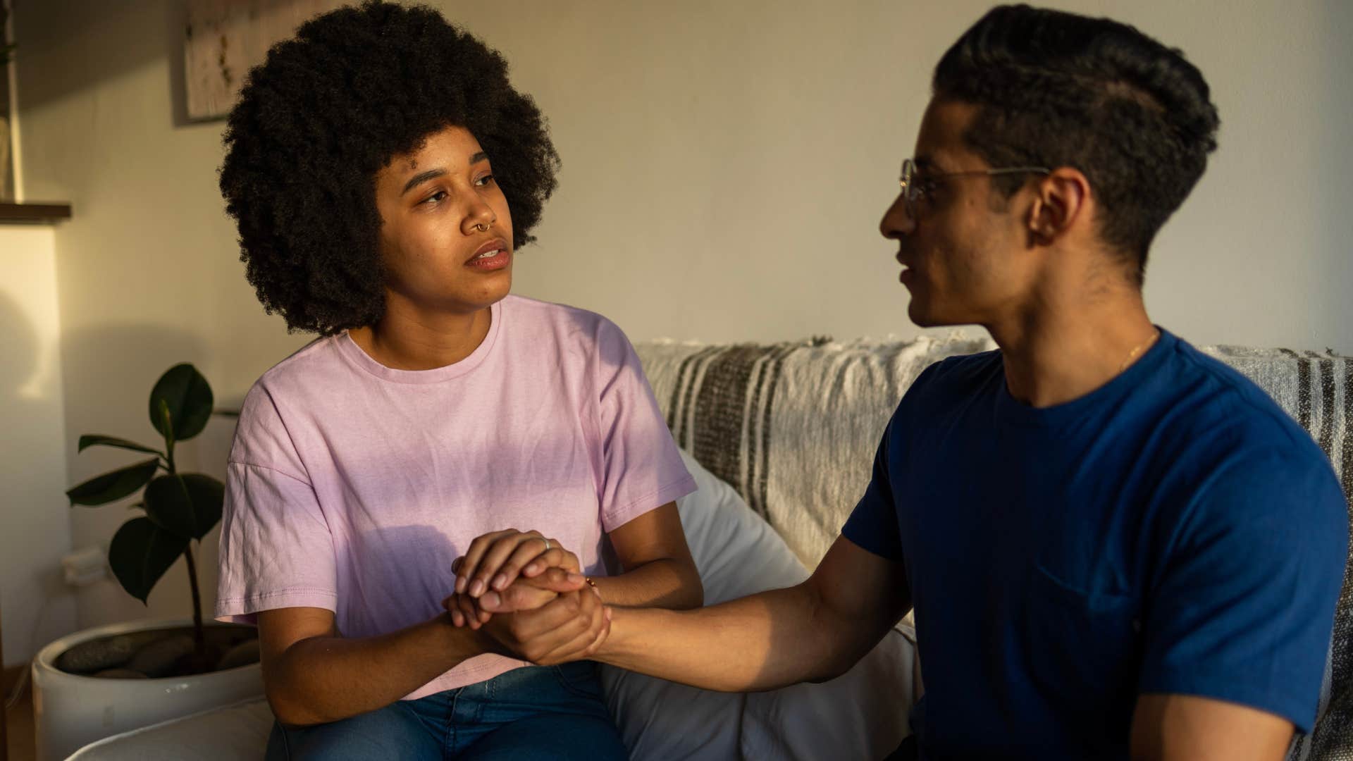 Woman looking at her boyfriend and holding his hand.