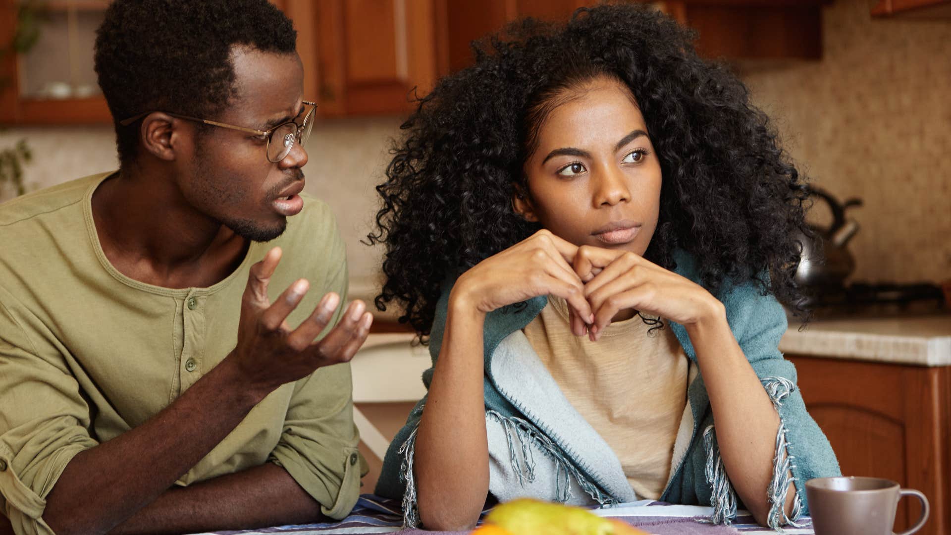 Man talking to his annoyed girlfriend at the table.