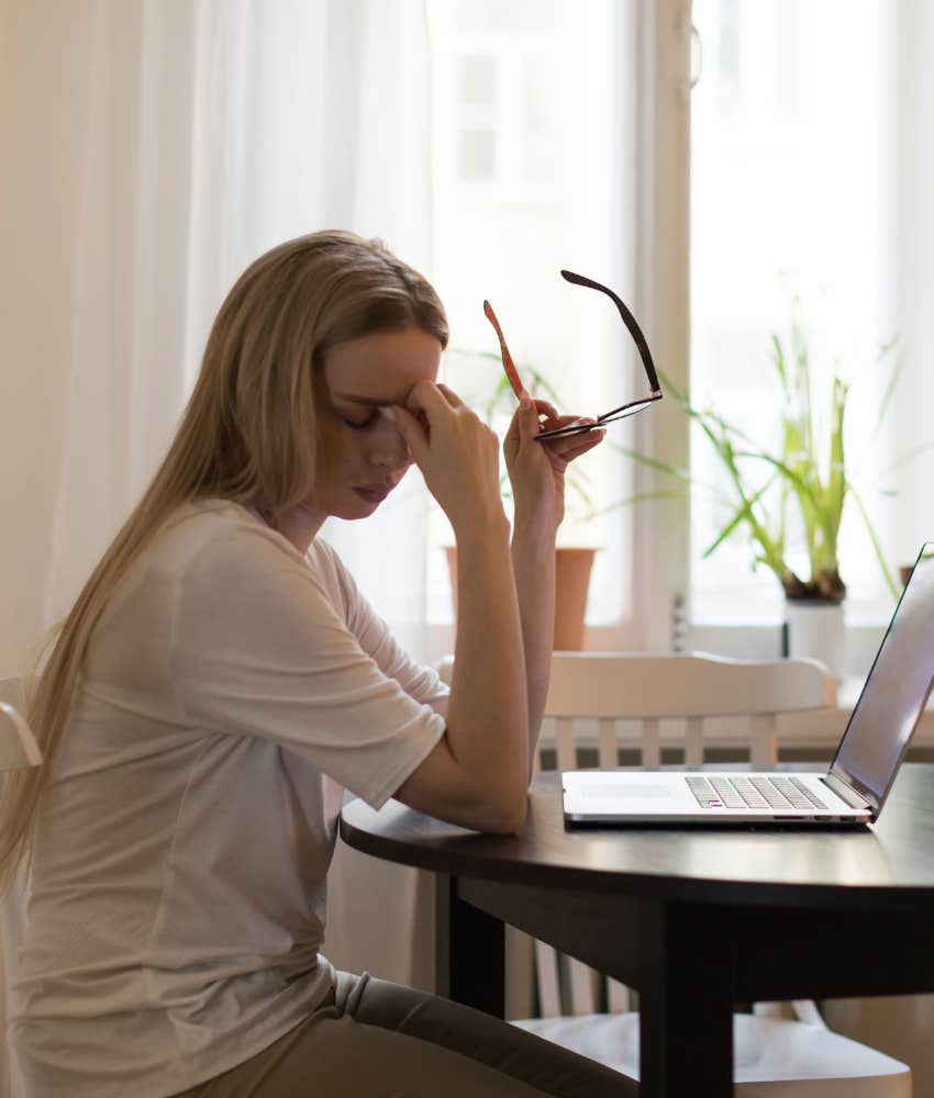 overworked and stressed out employee holding glasses with hand on face