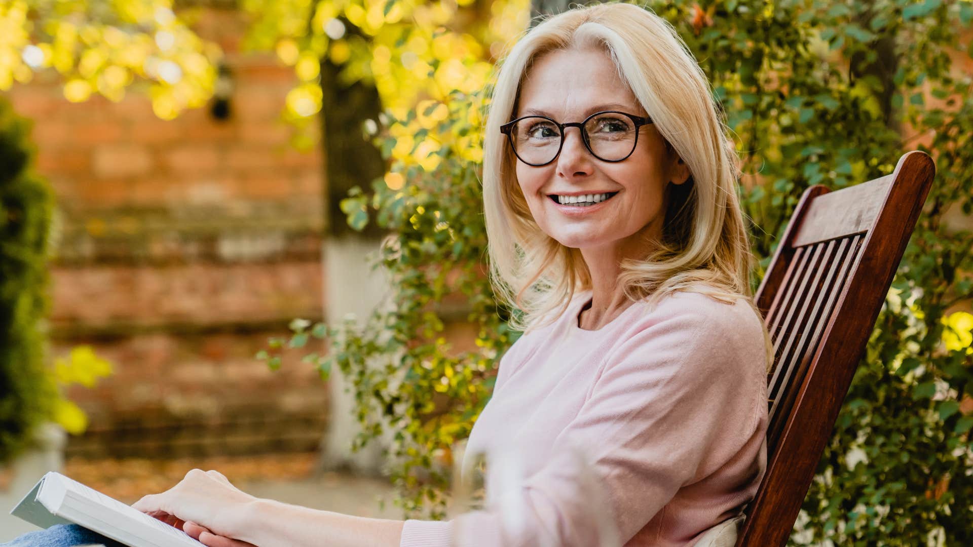 Adult woman smiling and reading a book.