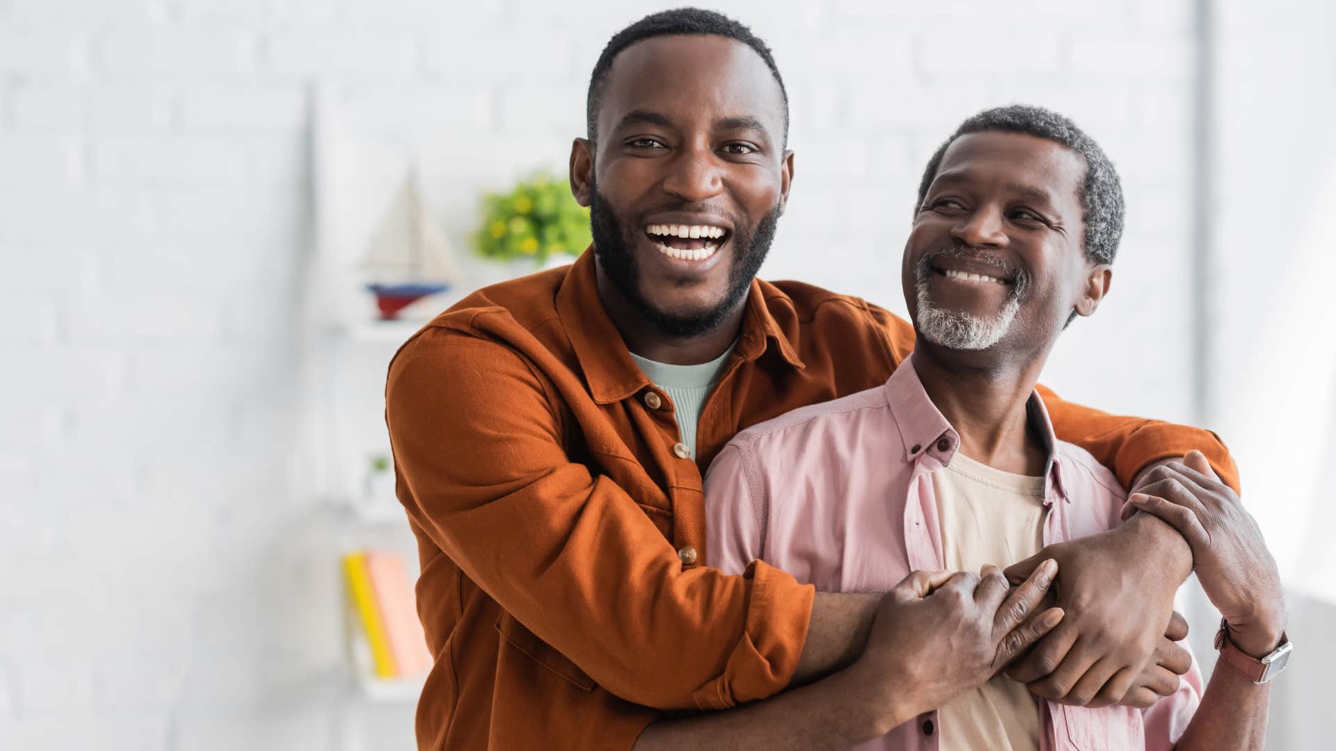 Adult man hugging his dad and smiling. 