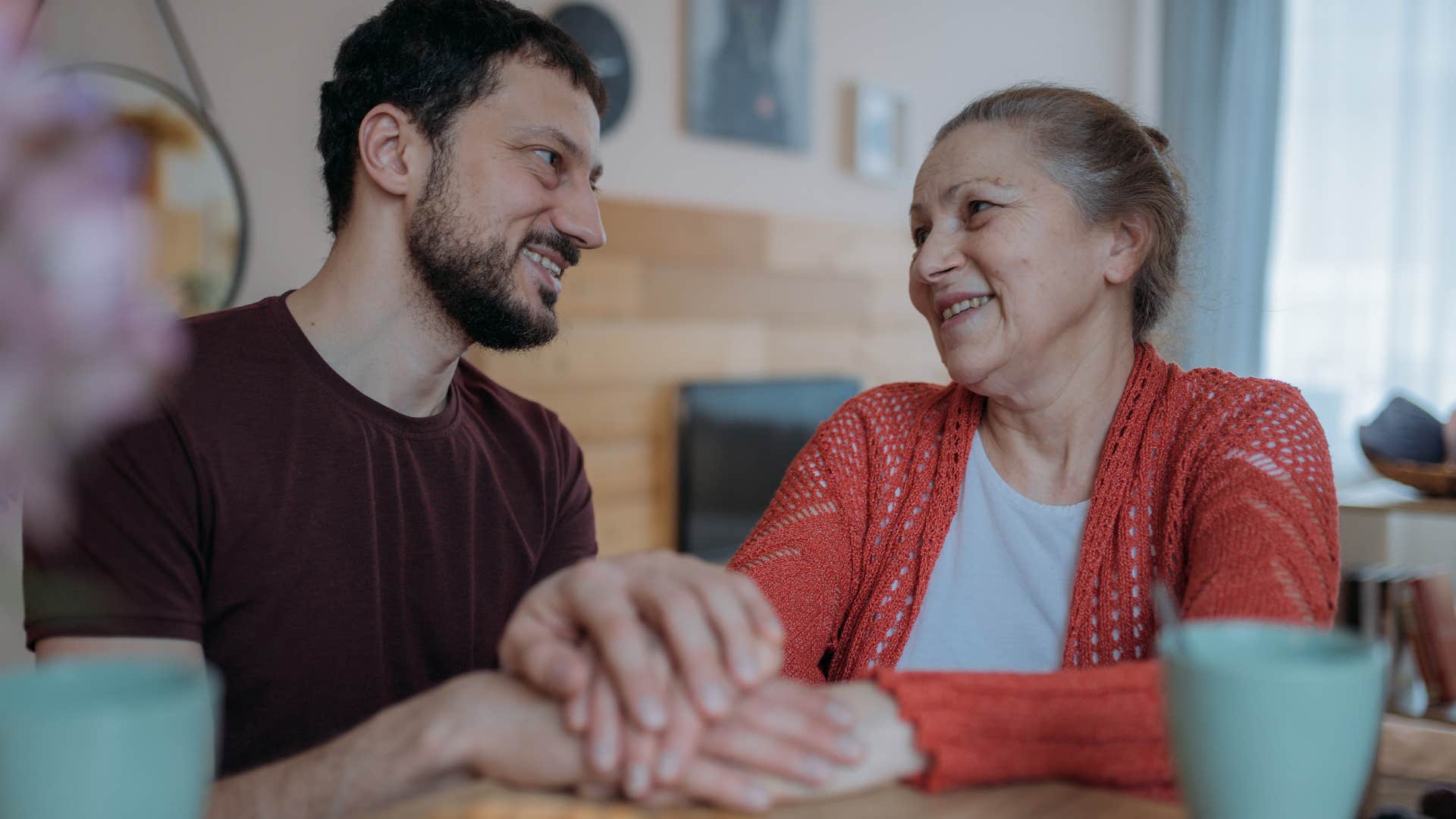 Adult man visiting with his mother in the kitchen.