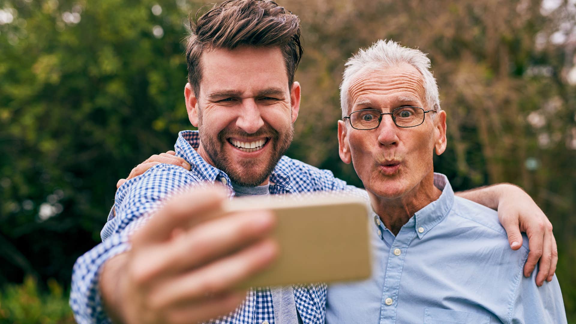 Adult man smiling with his dad taking a picture.