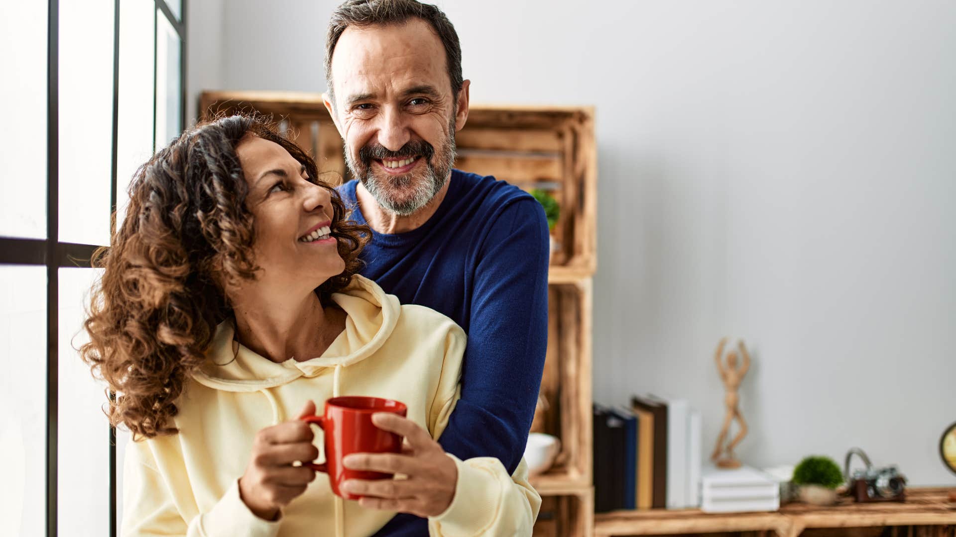 Older couple hugging and drinking coffee together.