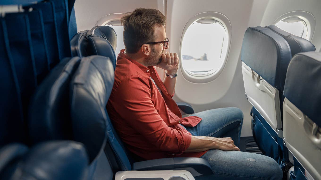 man sitting in window seat of plane next to middle seat